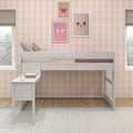 White wooden loft bed and small desk in pastel children's bedroom with pink gingham wallpaper and framed butterfly art