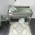Wooden twin loft bed with built-in desk, green bedding and pillows, boho area rug and bean bag in modern kids' bedroom