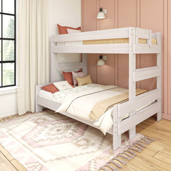 Whitewashed wooden twin-over-full bunk bed in a modern kids' bedroom with pink accent wall, floral bedding, wall sconces, and patterned area rug