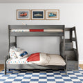 Gray wooden kids bunk bed with car-print bedding and pillows, red throw, three framed vintage car prints and blue checkered rug