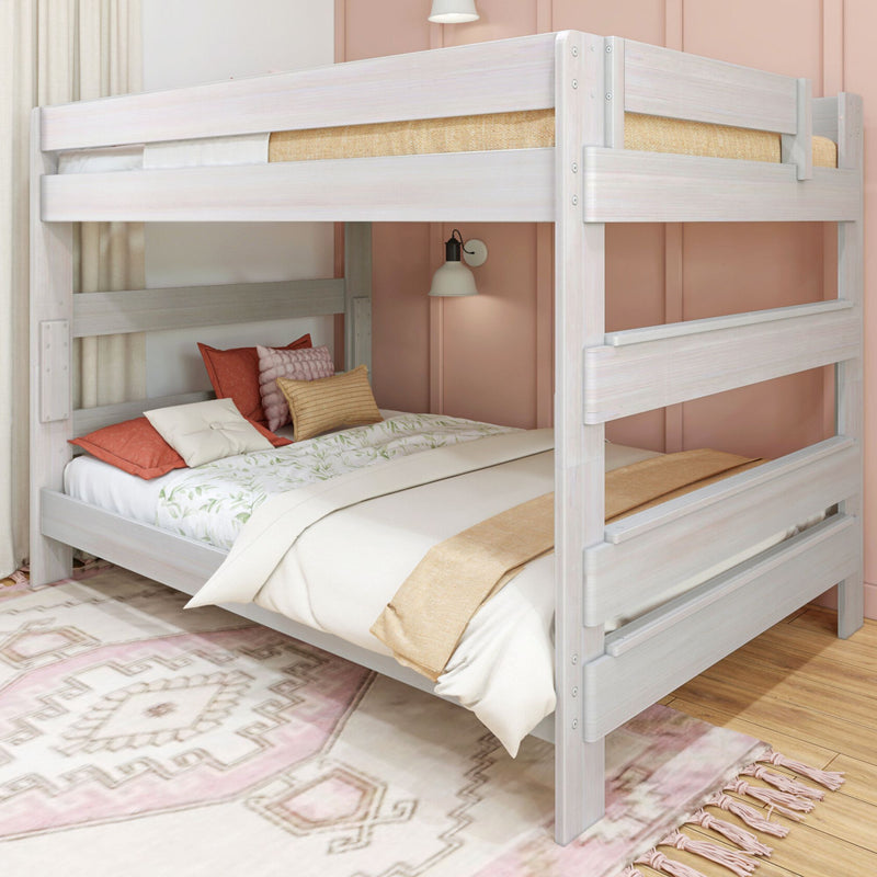Whitewashed wooden bunk bed in a kids' bedroom with floral bedding, terracotta and mustard pillows, pink accent wall and patterned rug