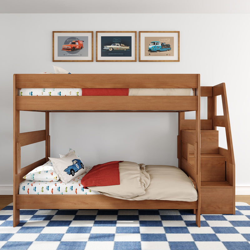 Wooden twin-over-twin bunk bed with built-in stairs, car-themed bedding and pillows, framed vintage car prints, and blue-check rug in kids bedroom