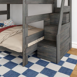 Grey wooden twin-over-twin bunk bed with built-in staircase storage, beige bedding and blue checkered rug in kids' bedroom