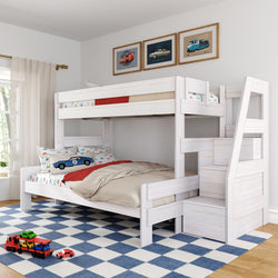 White wooden twin-over-full bunk bed with storage stairs in a bright kids' room, car-themed bedding, blue checkered rug and toy cars