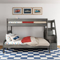 Gray wooden kids bunk bed with car-themed bedding, red throw, blue checkered rug and three framed vintage car prints in a children's bedroom