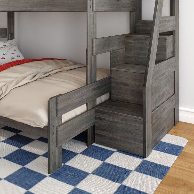 Gray wooden bunk bed with built-in storage stairs, beige bedding and car-print pillow on lower bunk in kids' bedroom with blue check rug