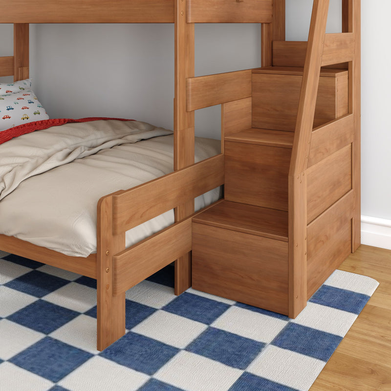 Natural wood bunk bed with built-in staircase storage, beige bedding and car-print pillow on blue checkered rug in kids' bedroom