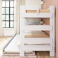 Whitewashed wooden bunk bed with pull-out trundle in a sunlit kids' bedroom, beige bedding, wall-mounted lamp and black-framed window