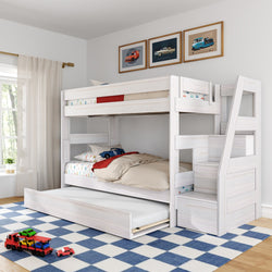 White wooden twin-over-twin bunk bed with staircase storage and pull-out trundle in a bright kids' bedroom, featuring car-themed bedding, blue check rug and framed car prints