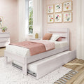 Cozy modern pink and white girl's bedroom with white wooden twin bed and pull-out trundle, blush bedding, floral framed wall art, white curtains and light wood floors