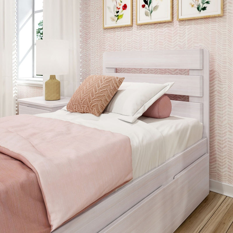 Blush pink bedroom decor with white wooden bed and trundle, blush bedding, knitted throw pillow and bolster, bedside table with ceramic lamp and floral wall art