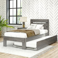 Modern farmhouse bedroom interior with gray wooden platform bed and pull-out trundle, neutral bedding and textured throw, chevron-patterned wallpaper, black grid window, bedside lamp and potted plant