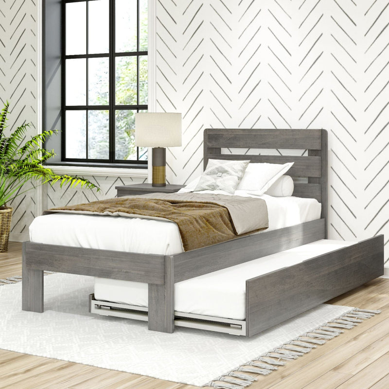 Modern farmhouse bedroom interior with gray wooden platform bed and pull-out trundle, neutral bedding and textured throw, chevron-patterned wallpaper, black grid window, bedside lamp and potted plant