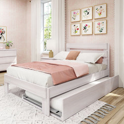 White wooden platform bed with pull-out trundle and blush pink bedding in a bright girls' bedroom with floral wall art, white curtains, bedside lamp, and matching dresser