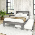 Modern farmhouse bedroom with gray wood platform bed, white linens and tan throw, geometric herringbone wallpaper, black grid windows, nightstand lamp and potted fern