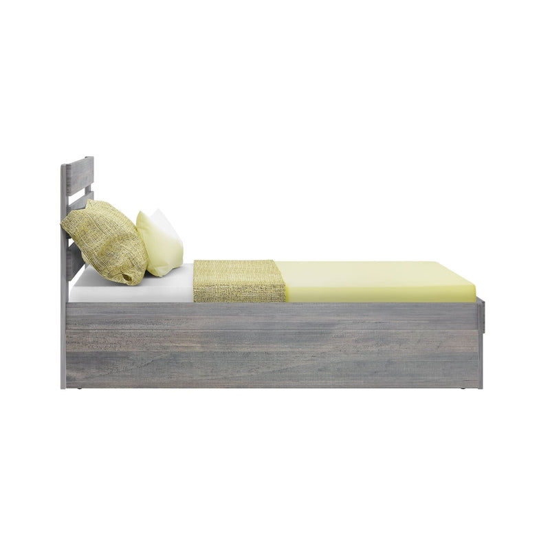 Single wooden bed with yellow bedding and pillows, side view.