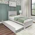 Whitewashed wooden twin trundle bed with green bedding, nightstand and lamp in a bright bedroom with green paneled accent wall and botanical wallpaper