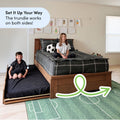 Space-saving wooden twin bed with pull-out trundle in kids' bedroom, smiling children on bed and trundle, soccer rug, wall drawings and black plaid bedding