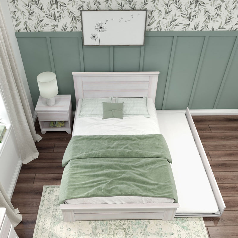 Cozy bedroom with trundle bed featuring green bedding, floral wallpaper, and wooden flooring.