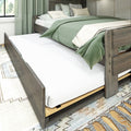 Rustic wooden trundle bed with green bedding and decorative pillows, white mattress and storage drawer in a cozy farmhouse bedroom with natural light