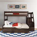 Dark wood bunk bed with staircase storage in kids' room, car-themed bedding, blue check rug and framed vintage car prints