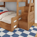 Solid wood bunk bed with built-in staircase drawers and safety rails, natural wood finish, children's car-print pillow and beige bedding on blue check rug