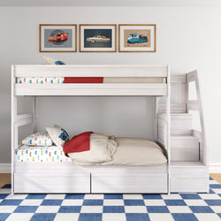 White wooden twin-over-twin kids' bunk bed with staircase, built-in storage drawers, car-print bedding, framed vintage car prints and blue checkered rug