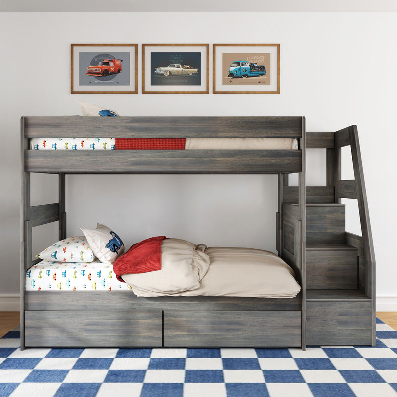 Gray wooden kids bunk bed with built-in stairs and under-bed storage drawers, colorful car-print bedding, red throw and framed vintage car posters on white wall in modern children's bedroom