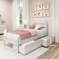 Girls bedroom with white wooden platform bed and under-bed storage drawers, blush pink bedding, floral framed wall art, sheer curtains and natural light