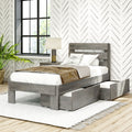 Modern farmhouse grey wood platform bed with under-bed storage drawers, neutral linens, geometric herringbone wallpaper, bedside lamp and black‑frame window