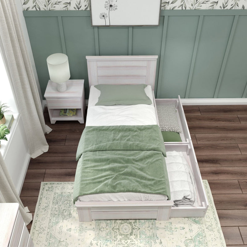 Whitewashed twin storage bed with pull-out underbed drawer, green bedding and pillow, bedside table with lamp, green paneled accent wall and hardwood floor