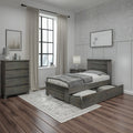Modern farmhouse bedroom with gray wood storage bed featuring pull-out drawers, matching dresser and nightstand, neutral bedding, patterned wallpaper, linen curtains and large black-framed window over dark hardwood floors