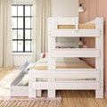 Whitewashed wooden bunk bed with pull-out trundle drawer in a bright kids' bedroom, hardwood floors, blush-pink accent wall, large black-framed window, neutral bedding and area rug