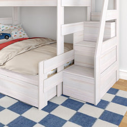 Space-saving white wooden bunk bed with built-in staircase storage, beige bedding and car-print pillows on blue check rug in modern kids' bedroom