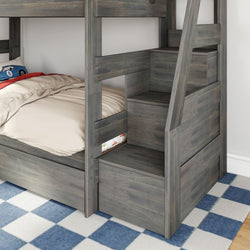 Gray wooden bunk bed with built-in storage stairs and pull-out drawers in kids' bedroom on blue checkered rug