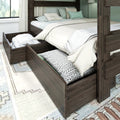 Dark wood bunk bed with open under-bed storage drawers holding pillows and linens, neutral beige and mint bedding, and a light rug in a modern farmhouse bedroom
