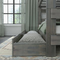Gray wood bunk bed with pull-out trundle mattress, green bedding and patterned pillow by a large window with sheer curtains in a modern bedroom