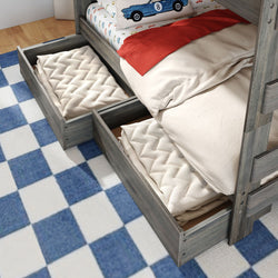 Gray wood twin bunk bed with under-bed storage drawers open showing quilted blankets, car-themed pillow and blue checkered rug in kids' bedroom