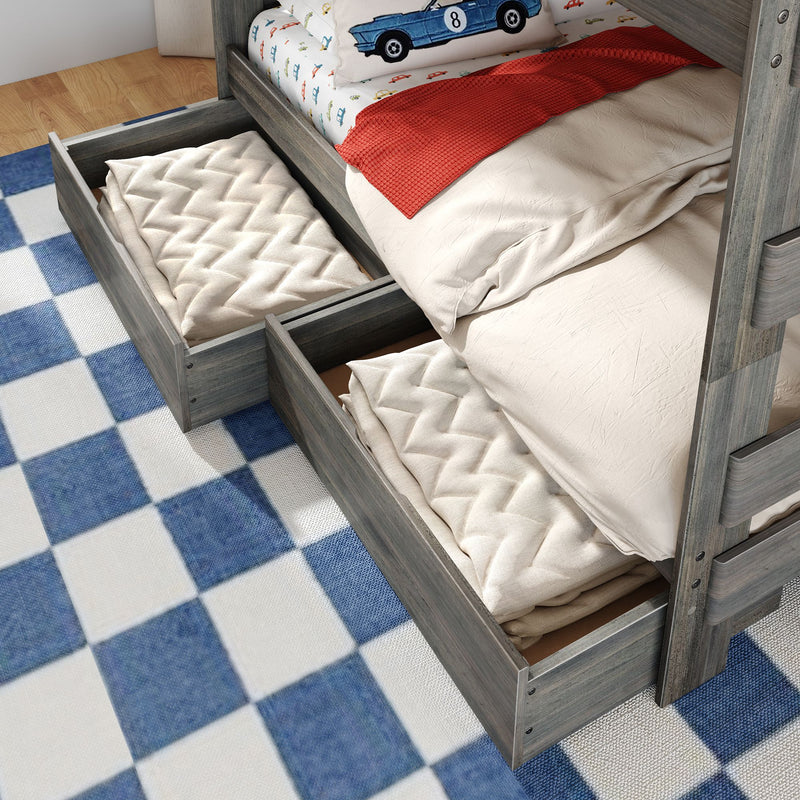 Gray wood twin bunk bed with under-bed storage drawers open showing quilted blankets, car-themed pillow and blue checkered rug in kids' bedroom