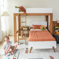 Wooden loft bunk bed in a bright kids' bedroom with ladder, rust-orange bedding, plush dinosaur, toy cars on a patterned rug and a child playing near a floor lamp