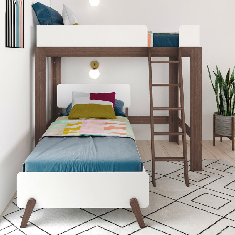 Modern twin-over-twin wooden bunk bed with ladder and white guardrails in kids' bedroom, colorful bedding, wall lamp and potted plant