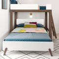 White and walnut wooden bunk bed with lower twin mattress, blue sheets and colorful quilt, ladder and wall sconce in kids' room