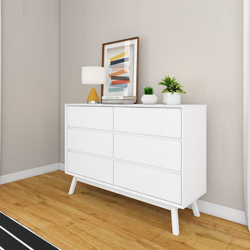Modern white dresser with minimalist decor and artwork in a stylish bedroom setting.