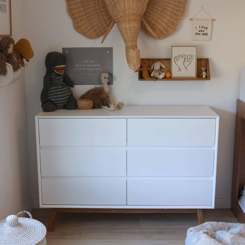 Children's room with a modern white dresser, stuffed animals, and decorative wall art.