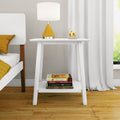 Minimalist white bedside table with yellow modern lamp, stack of books on lower shelf, hardwood floor in contemporary bedroom