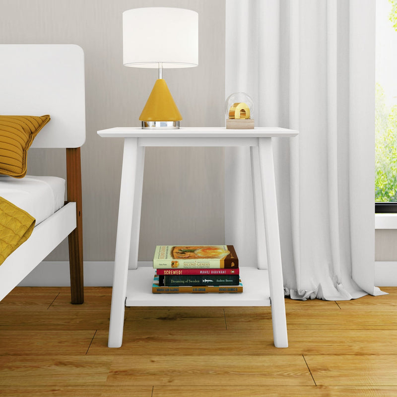Minimalist white bedside table with yellow modern lamp, stack of books on lower shelf, hardwood floor in contemporary bedroom