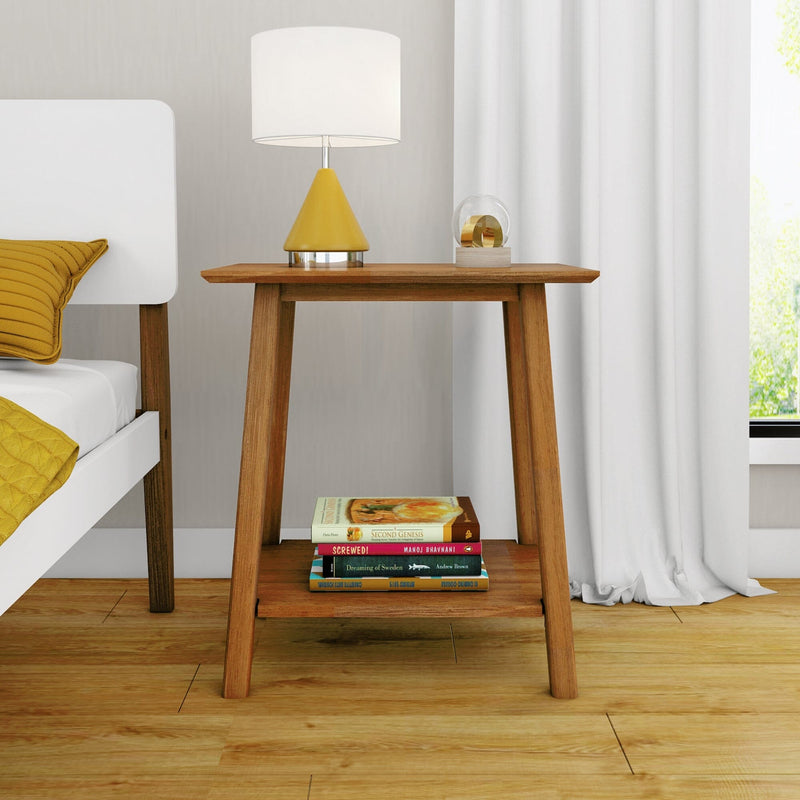 Mid-century modern wooden nightstand beside a white bed, topped with a white drum lamp with yellow cone base and glass orb, stacked books on the lower shelf, yellow pillows, hardwood floor and white curtains — stylish bedroom decor.