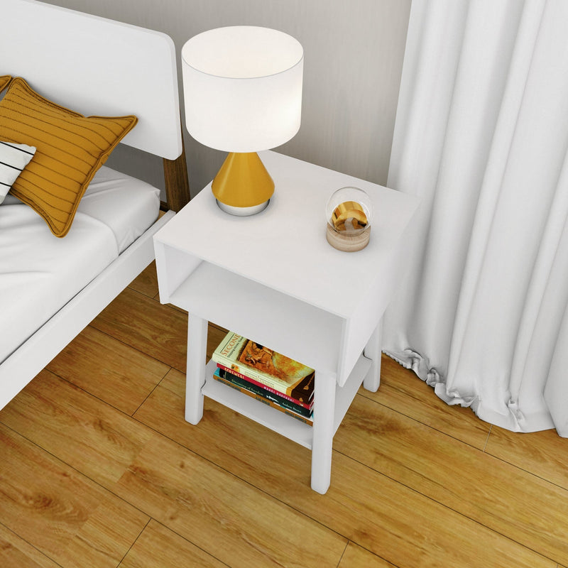Modern white bedside table nightstand with yellow lamp and mustard pillow, books on lower shelf on hardwood floor in minimalist bedroom