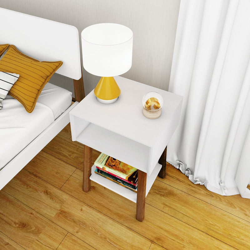 Modern white bedroom nightstand with wooden legs and shelf, yellow bedside table lamp, stacked books on lower shelf, mustard accent pillow and hardwood floor