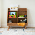 Wooden cubby toy storage shelf in children's bedroom with colorful blocks, soccer ball, stuffed animals, yellow blanket and toy car artwork